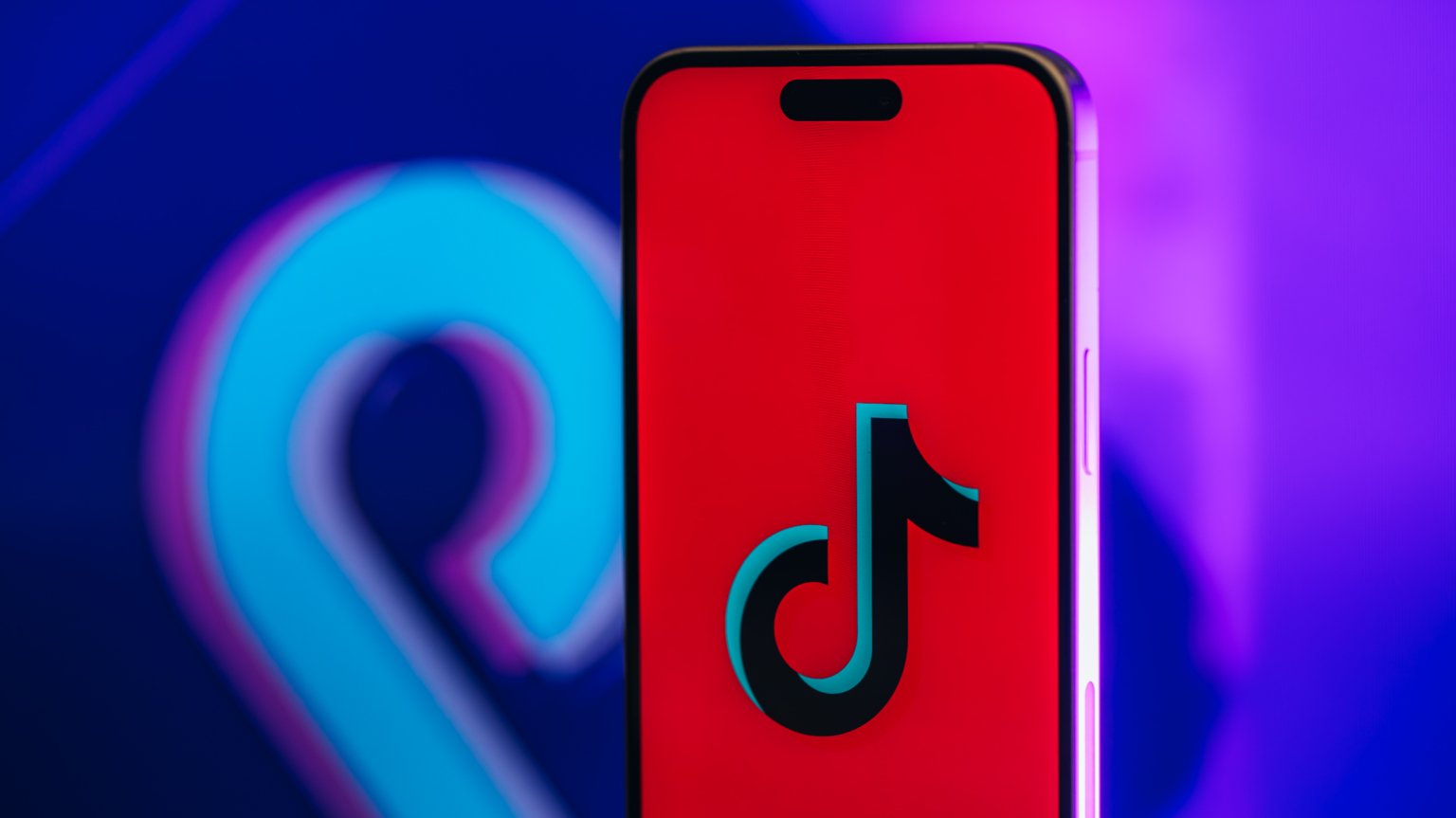 A phone displays a red screen with the TikTok logo. 
