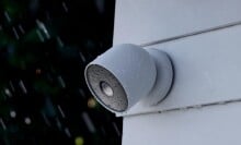 the google nest cam on the side of a white house while it's raining