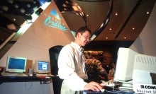 Under a giant AOL logo, a man looks at a 1990s computer. 