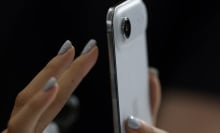 A hand with painted nails taps on the screen of a new iPhone Air.