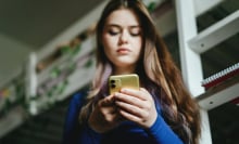 Girl looks down at phone in her hands.