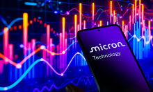 Micron logo on smartphone screen in front of stock ticker