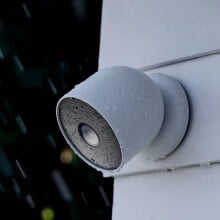 the google nest cam on the side of a white house while it's raining