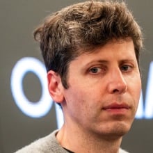 Sam Altman looking pensive before an OpenAI logo.