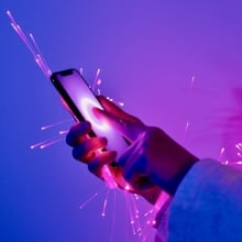 cybersecurity concept art of arm holding smartphone wrapped in glowing fiber optic cables