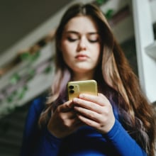 Girl looks down at phone in her hands.
