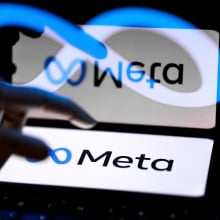 A hand hovers over a screen showing the Meta logo. The image is reflected and distorted.