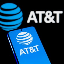 A phone displays the blue AT&T logo in front of a dark background.