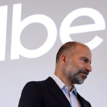 The Uber logo above its CEO, who is looking pensive