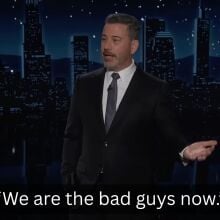A man in a suit stands on a talk show stage. The caption at the bottom reads, "We are the bad guys now."