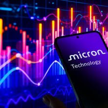 Micron logo on smartphone screen in front of stock ticker