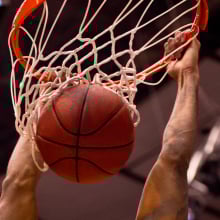 Male basketball player dunks the ball with two hands