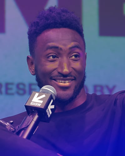 Marques Brownlee pointing while sitting in a chair.