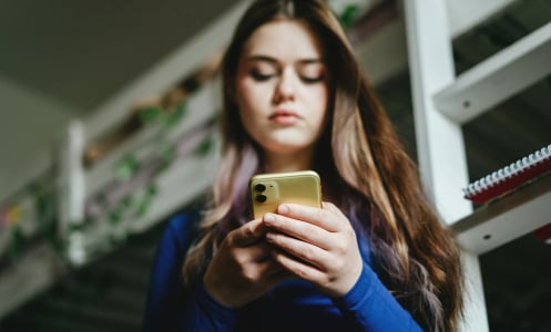 Girl looks down at phone in her hands.