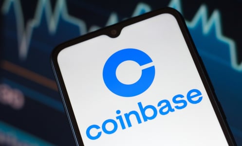 The Coinbase logo is seen displayed on a smartphone screen.