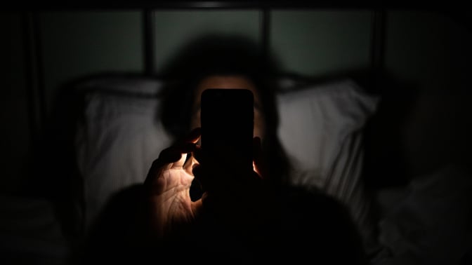 man using smartphone at night in bed