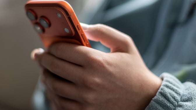 A close up photo of a child's hand holding an iPhone.