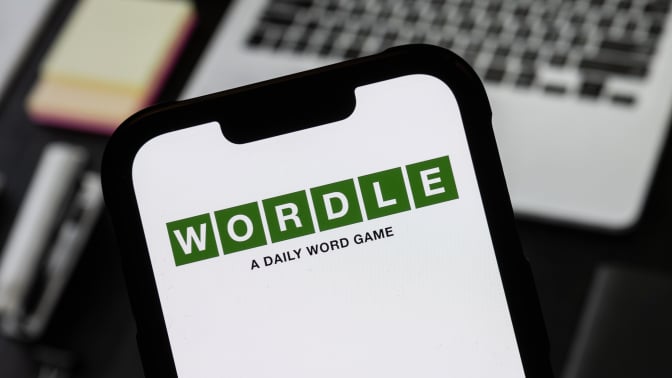 A smart phone shows a white screen with the Wordle logo on it.