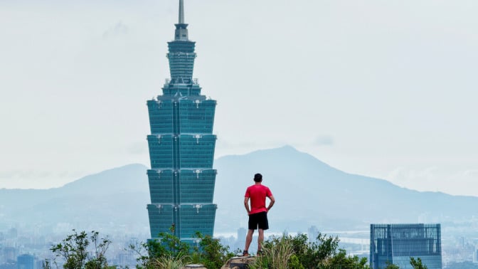 Alex Honnald standing next to the Taipei 101 skyscraper