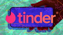Hand holding phone with Tinder logo against abstract background