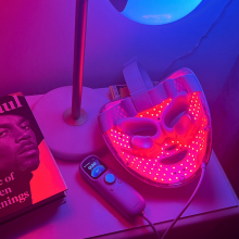 Shark red light face mask, lamp, and book on nightstand
