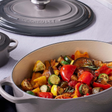 Gray Le Creuset casserole dish with vegetables insideq
