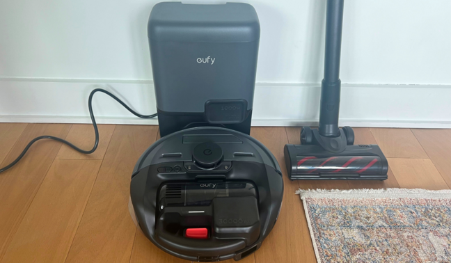 Robot vacuum and stick vacuum attachment sitting against wall on hardwood floor